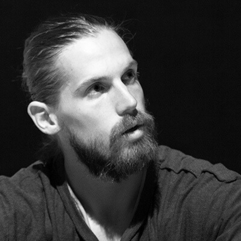 Black and white portrait of a young man with a beard and long fair hair pulled back.