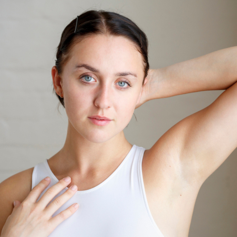 Headshot of a young woman with dark hair pulled back against a grey background.