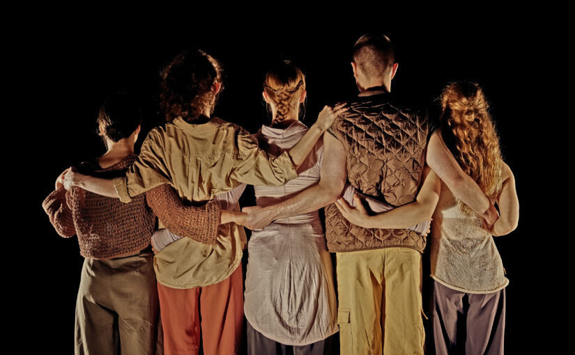 Image of five people with their backs to the camera, linking arms by the waist.