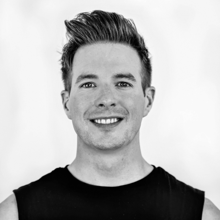 Black and white headshot of a man with short hair and a black t-shirt.