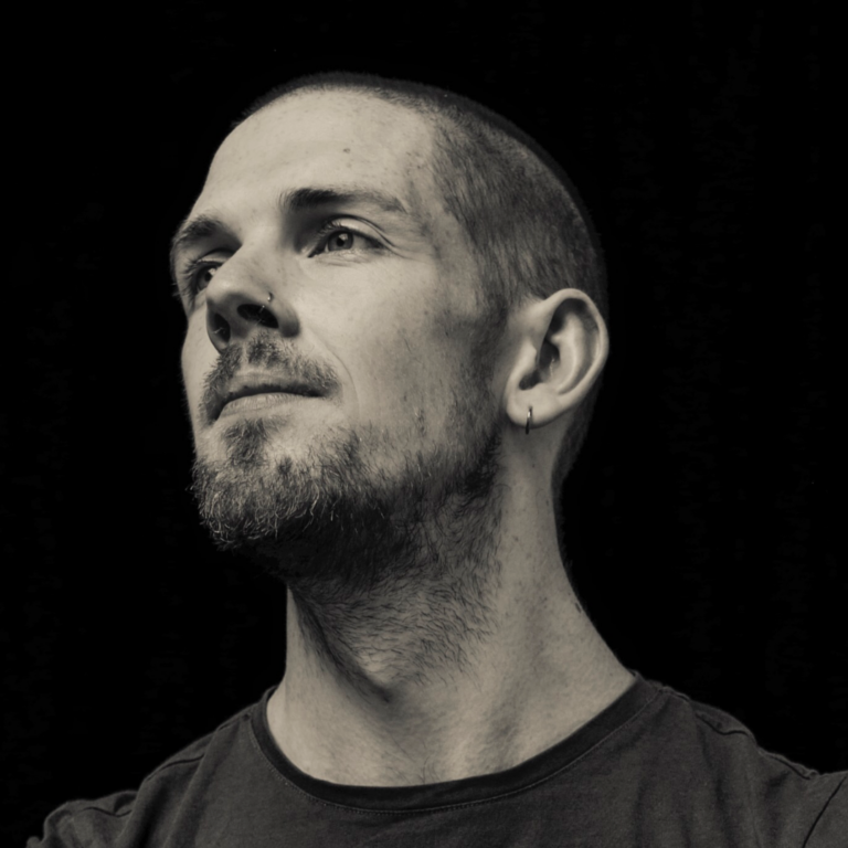 Black and white headshot of a man with short hair and a beard.