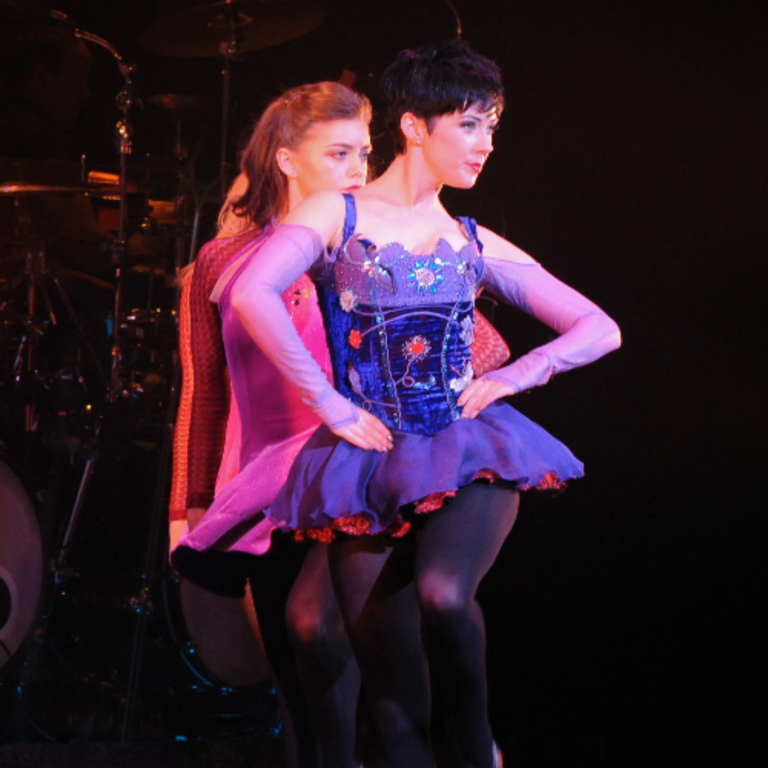 Image of two traditional Irish dancers performing in a purple costume.