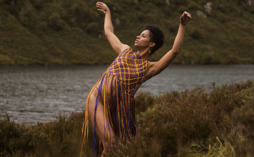 Image of a dancer against a landscape of river and green mountains.