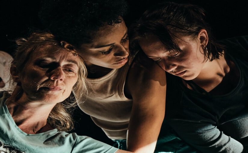 Close-up of of three dancers against a dark background.