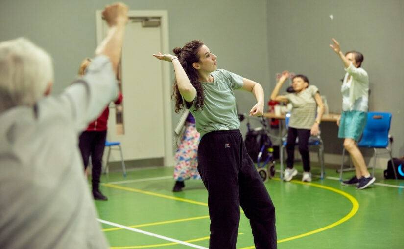 Image of a group of people dancing in a green sports hall.